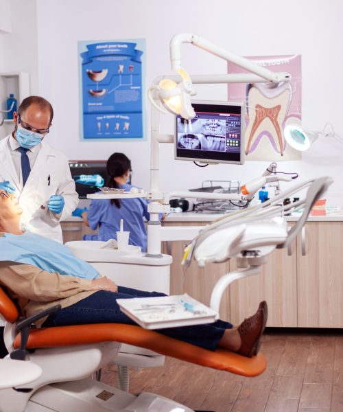 Dentist doing a dental treatment and intervention. on senior woman. Elderly patient during medical examination with dentist in dental office with orange equipment.